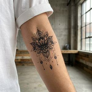 Ornamental lotus mandala temporary tattoo with chandelier pendant drops and dotwork detailing on white background.