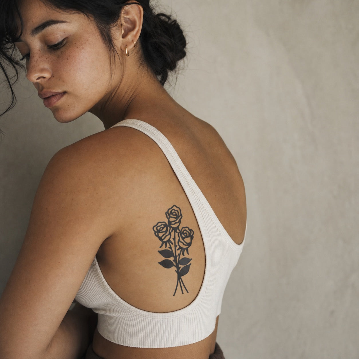 Three rose bouquet temporary tattoo in solid blackwork on white background, crossed stems with leaves and three open blooms.