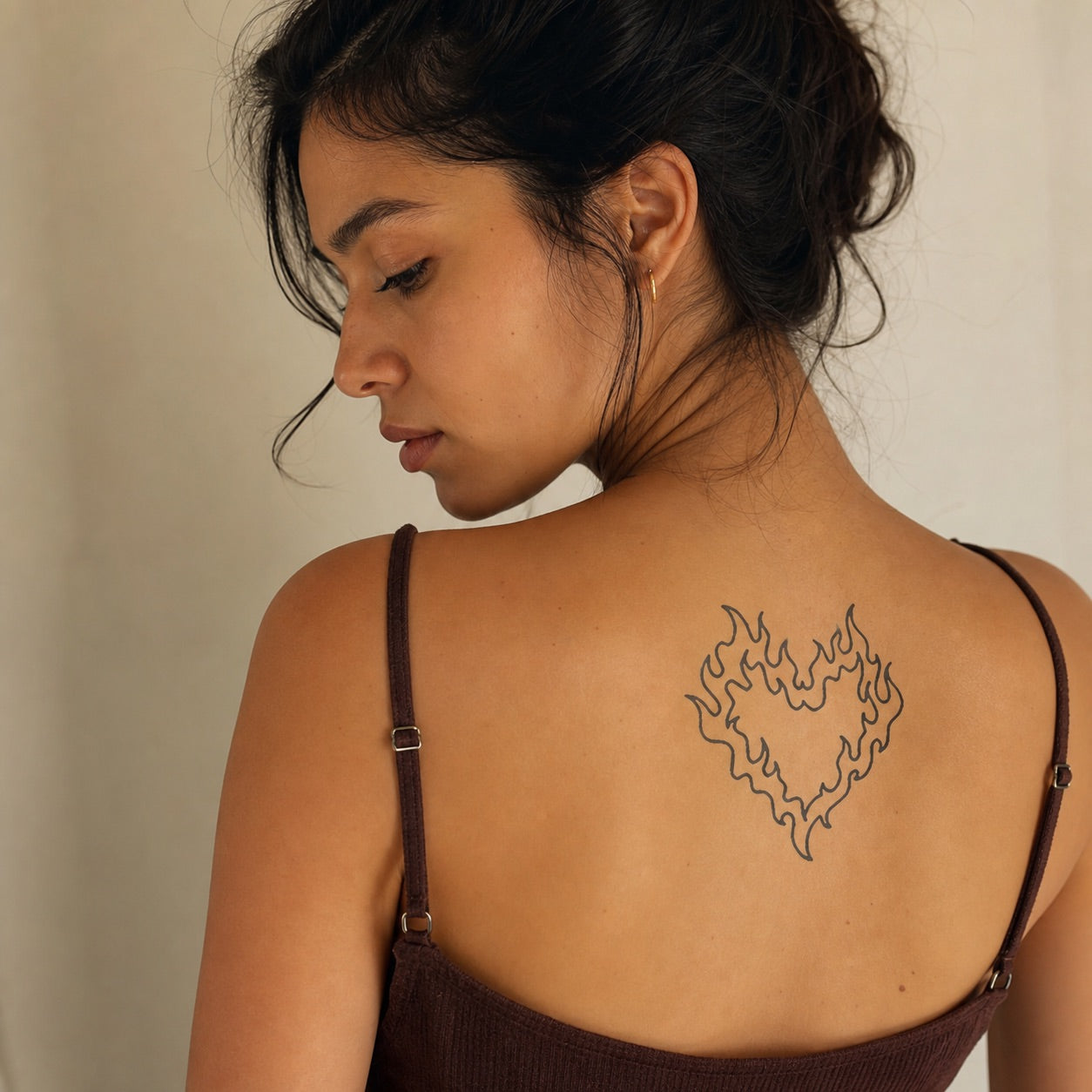 Flaming heart outline temporary tattoo in bold linework on white background, fire forming a heart silhouette.