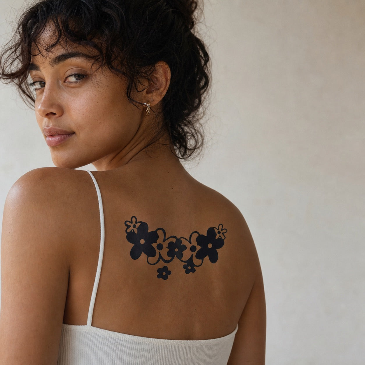Blackwork floral garland duo temporary tattoo — two curved daisy arcs with vine connectors on white background.