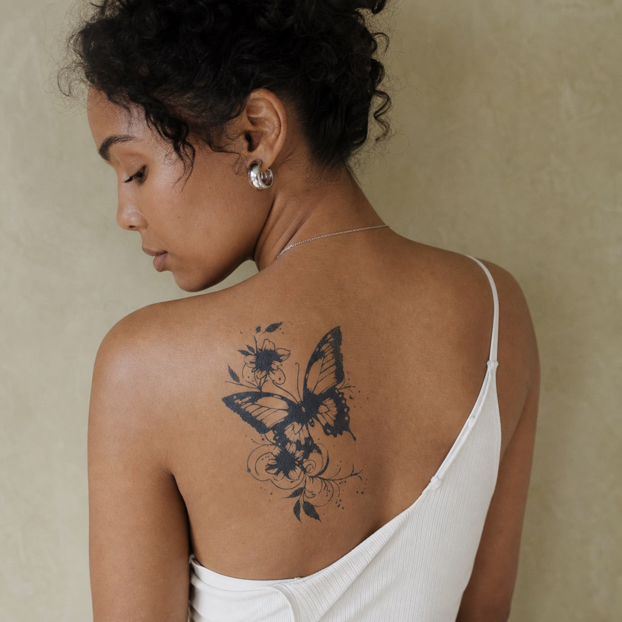 Bold blackwork butterfly with floral and vine motifs, ink splatter details, temporary tattoo on white background.