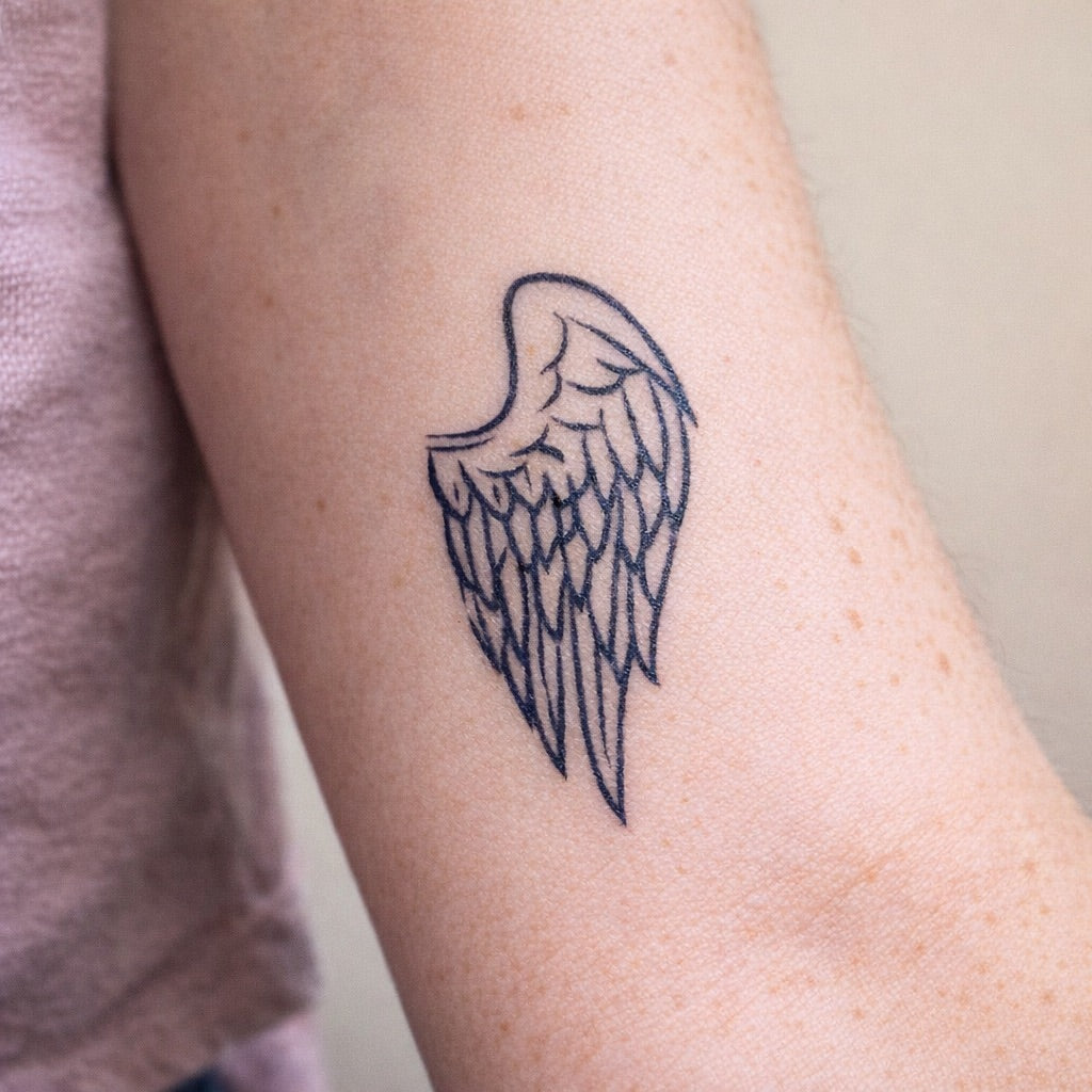 Single angel wing fine line tattoo in blue-black ink